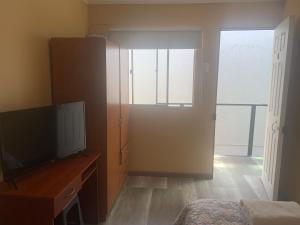a bedroom with a television and a door to a balcony at Hostal Iria in Antofagasta