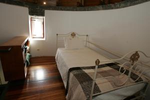 um quarto com uma cama e piso em madeira em O Moinho Da Bibi em Sete Cidades