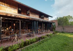 un restaurante con mesas y sillas fuera de un edificio en Athita The Hidden Court Chiang Saen Boutique Hotel SHA Plus CERTIFIED en Chiang Rai