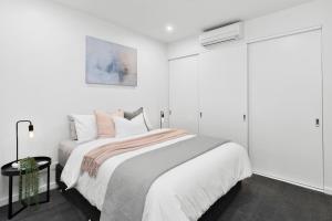 Dormitorio blanco con cama y pared blanca en Pier Point 404- Luxe on Geelong Waterfront, 2 BDRM en Geelong