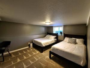 a bedroom with two beds and a chair and a window at Ultra Comfy, Spotless & Spacious, Private Home in Boyne, Dogs Ok, Walk to Town in Boyne City