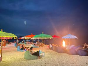 grupa ludzi siedzących na plaży pod parasolami w obiekcie Gili Lumbung Bungalow w Gili Air