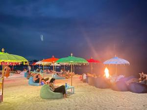 a group of people sitting on the beach under umbrellas at Gili Lumbung Bungalow in Gili Air