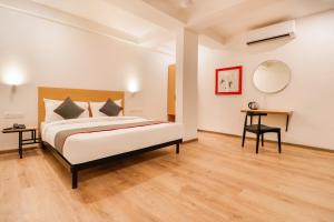 a bedroom with a bed and a table and a mirror at Townhouse South Tukoganj in Indore