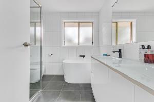 a white bathroom with a tub and a sink at Sleepy Shackell - Echuca Moama Holiday Accommodation in Echuca