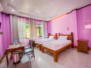 a bedroom with two beds and purple walls at Baan Rung Tawan in Ban Bang Nao