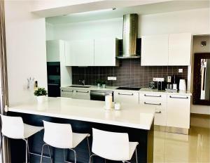 a white kitchen with white cabinets and white stools at The Penthouse 401 in Larnaca