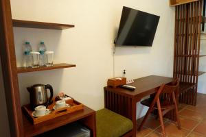 Habitación con escritorio y mesa con TV. en Rumah Bata Guest House, en Licin