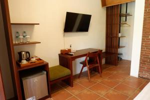Habitación de hotel con escritorio y TV en Rumah Bata Guest House, en Licin