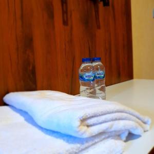 dos botellas de agua sentadas en una mesa con toallas en Candi Panggung Family Guest House Syariah, en Malang