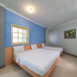 1 dormitorio con 1 cama grande y pared azul en Candi Panggung Family Guest House Syariah, en Malang