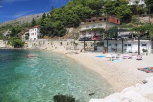 a beach with a group of people in the water at Apartments by the sea Sumpetar, Omis - 4827 in Jesenice
