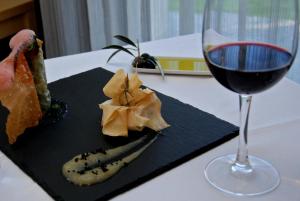 a glass of wine sitting next to a plate of food at Quinta De Casaldronho Wine Hotel in Lamego