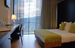ラメーゴにあるQuinta De Casaldronho Wine Hotelのベッド、デスク、窓が備わるホテルルームです。