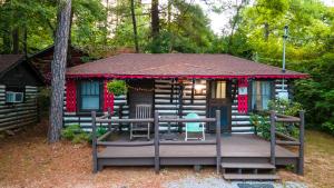 una cabaña en el bosque con terraza y sillas en Log Cabin Motor Court en Asheville
