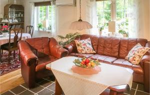 a living room with a brown leather couch and a table at Nice Home In Halmstad With Kitchen in Öppinge