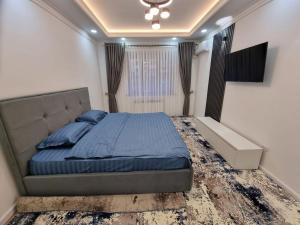 Schlafzimmer mit einem Bett mit blauer Bettwäsche und einem Fenster in der Unterkunft Квартира в аренду Tashkent in Taschkent