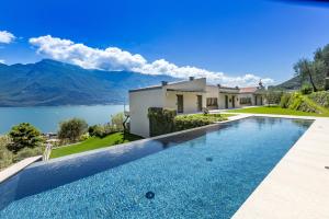 a swimming pool in front of a house with a lake at LLAC Living Nature Hotel in Limone sul Garda