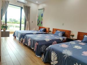 1 dormitorio con 2 camas con colchas azules y ventana en GiaBinh Homestay en Cao Bằng