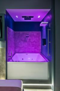 un bagno viola con vasca e illuminazione viola di Enjoy Art a Napoli