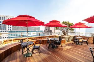a balcony with tables and chairs with red umbrellas at Ramada Hotel and Suites Seoul Namdaemun in Seoul