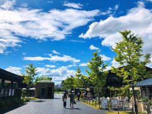 Gente caminando por una calle bajo un cielo azul con nubes en Peace House Suzunami, en Osaka