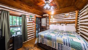 a bedroom with a bed and a ceiling fan at Log Cabin Motor Court in Asheville