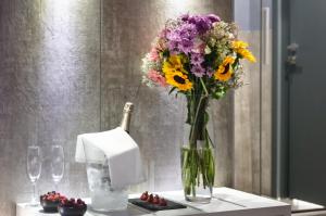 un vaso di fiori su un tavolo con bicchieri da vino di Enjoy Art a Napoli Altre 21 foto
