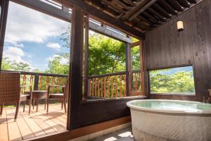 Großes Zimmer mit einer Badewanne auf einer Terrasse mit Fenstern. in der Unterkunft Hakone Fontaine Bleau Sengokutei in Hakone