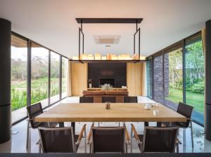 a dining room with a large wooden table and chairs at Gliding Villa in Khao Yai in Mu Si