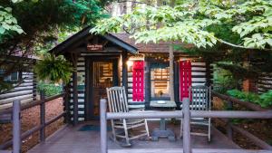 a small house with red doors and two chairs at Log Cabin Motor Court in Asheville