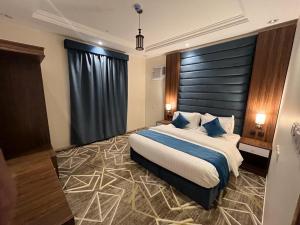 um quarto com uma cama grande e almofadas azuis em فيو إن للشقق الفندقية - المحالة em Abha