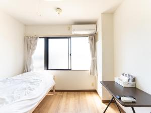 a bedroom with a bed and a desk and a window at Tabist Daibou Ichihara Mens Only in Ichihara