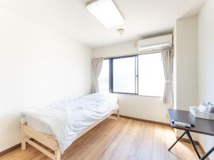 a bedroom with a bed and a desk and a window at Tabist Daibou Ichihara Mens Only in Ichihara
