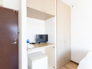 a bedroom with a desk with a television and a closet at Tabist Daibou Ichihara Mens Only in Ichihara