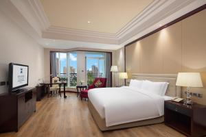 a hotel room with a large white bed and a desk at C&D Hotel,Putian in Putian