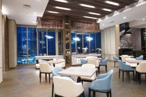 a restaurant with tables and chairs and a view of the city at Platinum Hotel Tunjungan Surabaya in Surabaya