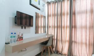 a room with a desk and a television and curtains at RedDoorz Near Iloilo International Airport in Iloilo City