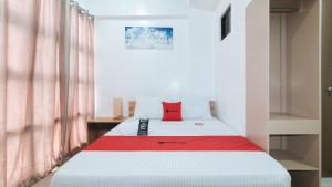 a bedroom with a bed with a red pillow on it at RedDoorz Near Iloilo International Airport in Iloilo City