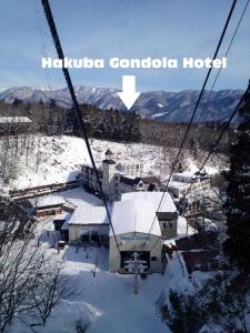 a ski lift with a house in the snow at Hakuba Gondola Hotel in Hakuba