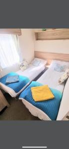 two twin beds in a room with a window at Sea let’s selsey in Selsey
