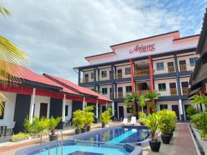 un hotel con piscina frente a un edificio en Anjung Villa en Pantai Cenang
