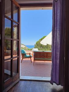 eine offene Glastür zu einer Terrasse mit einer Bank in der Unterkunft Padullella, mare e sole!! in Portoferraio