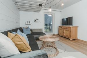 a living room with a couch and a tv and a table at Seeblickwohnung Liesl in Buchau