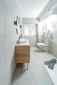 Baño blanco con lavabo y espejo en Seeblickwohnung Liesl, en Buchau