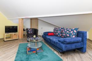 a living room with a blue couch and a glass table at Ferienwohnungen Haus Hasenweide in Stedesdorf