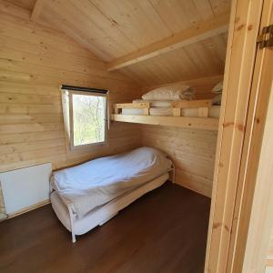 a small room with a bed in a log cabin at Vakantiehuisje met keuken, 2 slaapkamers en woonkamer in Zwiggelte