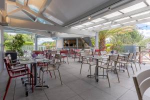 a dining room with tables and chairs on a patio at Abor Hôtel, Mont de Marsan in Saint-Pierre-du-Mont