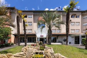 een gebouw met palmbomen ervoor bij Hotel Abor in Saint-Pierre-du-Mont