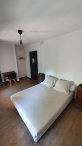 Cama blanca grande en habitación con suelo de madera en L'Auberge du Campos, en Saint-Pierre-Duchamp